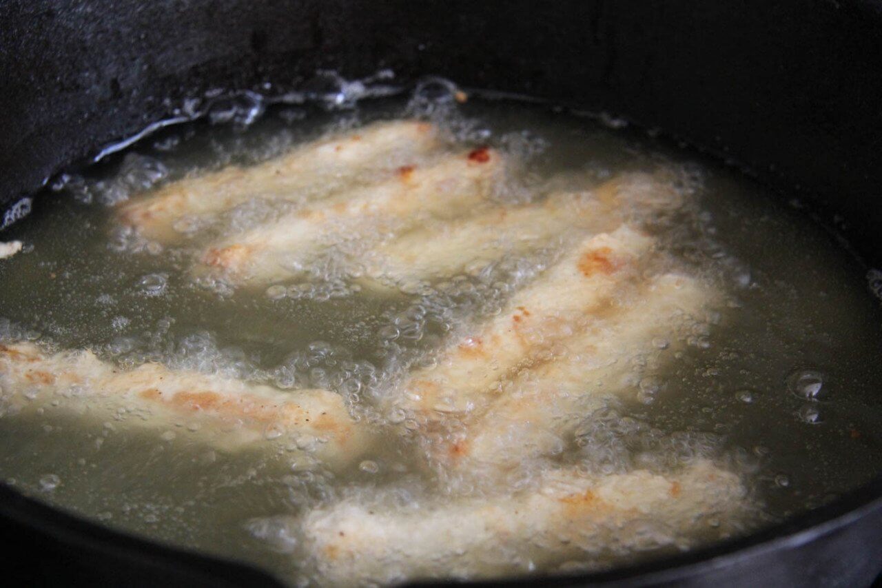 Поочерёдно опускаем подготовленные палочки сначала в сливочную смесь, а затем снова в муку. После этого обжариваем сырные палочки на сковороде около 1-2 минут.