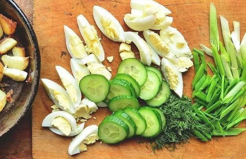 Нарезка вареных яиц, огурцов и свежей зелени
