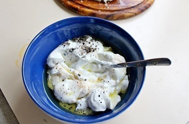 Смешиваем йогурт, 1 ст.л. оливкового масла, соль и чёрный молотый перец. Заправляем смесью салат.