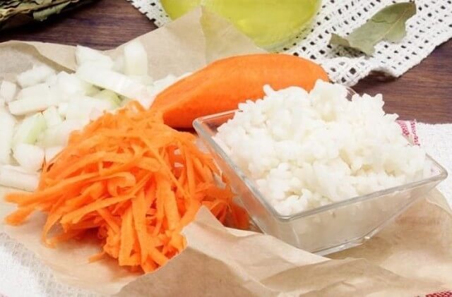 Морковь промыть и натереть на крупной тёрке. Лук нарезать крупными кубиками. Рис отварить до готовности. На сковороде обжарить сначала лук до золотистого цвета, а потом добавить морковь и тушить до мягкости.