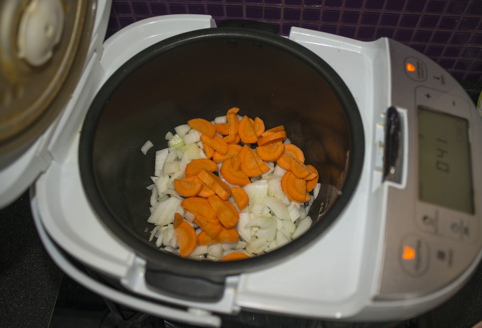 Морковку, лук и чеснок очистим. Чеснок измельчим ножом, лук нашинкуем кубиками или кусочками, а морковь полукольцам. Заливаем масло в чашу и устанавливаем режим "Жарка" на 45 минут. Опустим нарезанные ингредиенты и обжариваем их 10 минут.