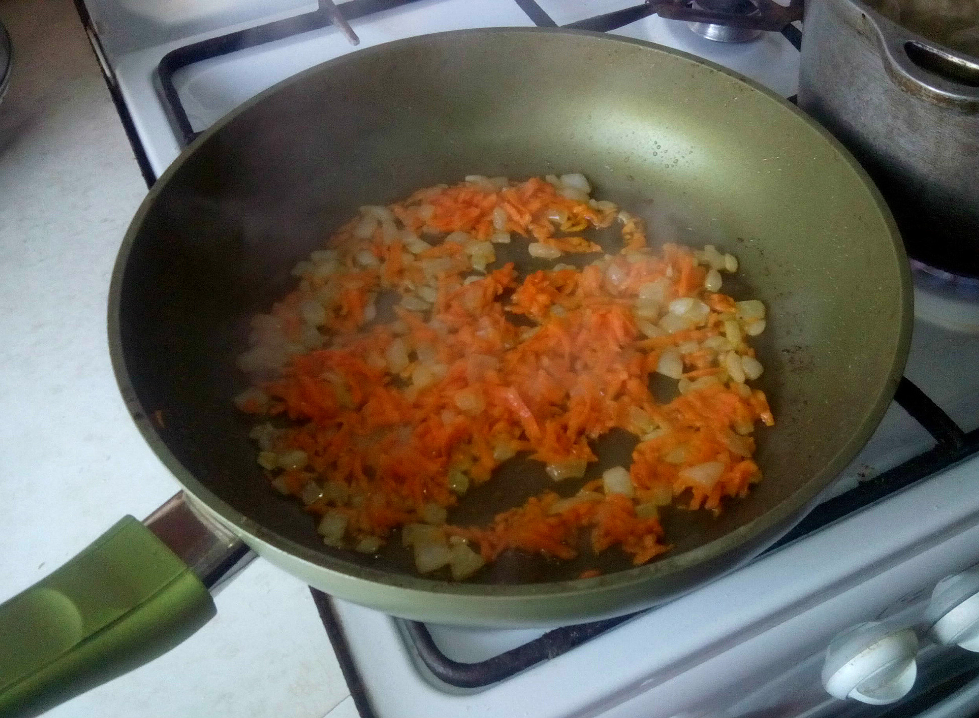 Параллельно, пропустим через среднюю тёрку морковь, а лук мелко нашинкуем. Сначала обжарим до золотистого цвета лук. Добавим морковь и обжариваем до готовности моркови.
