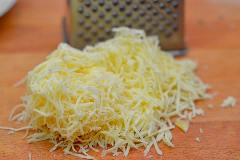 <p>Через мелкую тёрку пропускаем твёрдый сыр. В посудину выливаем сливки и добавим в них тимьян, горчицу, соль, перец. Выдавим чеснок и перемешаем.</p>