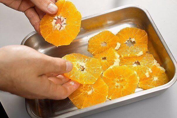Духовой шкаф разогреем до 200 градусов. В глубокую форму одним слоем выложим нарезанный апельсин.