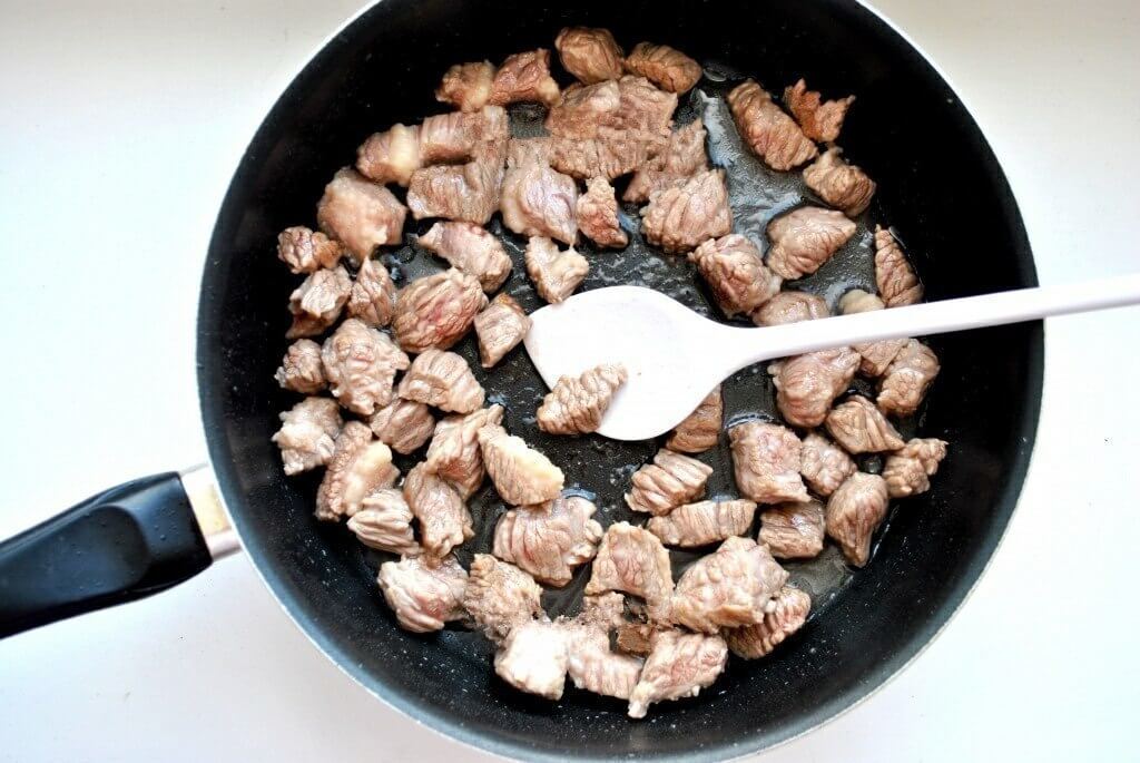 В глубокой сковороде разогреваем растительное масло. Ставим большой огонь и порционно обжариваем мясо. Таким образом, мясо должно именно обжариться, а не тушиться.