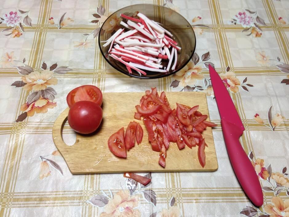 Промоем помидоры и нарежем их соломкой, как и палочки. Пару брусочков оставляем для украшения.