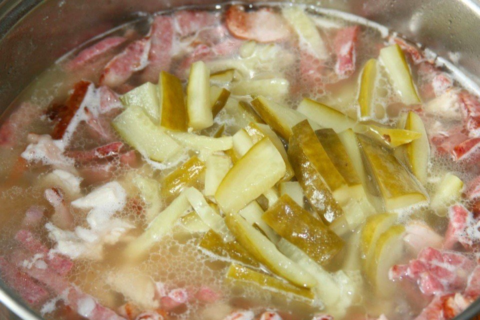 Теперь в солянку добавляем огурцы, нарезанные кольцами маслины и заливаем рассол.