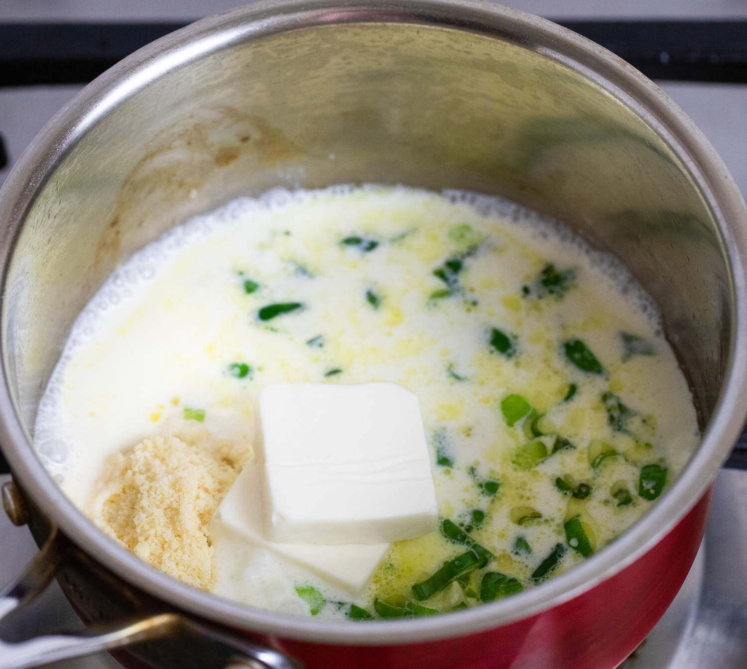 Твердый сыр натереть. Добавить его вместе с молоком и плавленым сыром в кастрюлю. Тщательно перемешать до образования однородной консистенции.