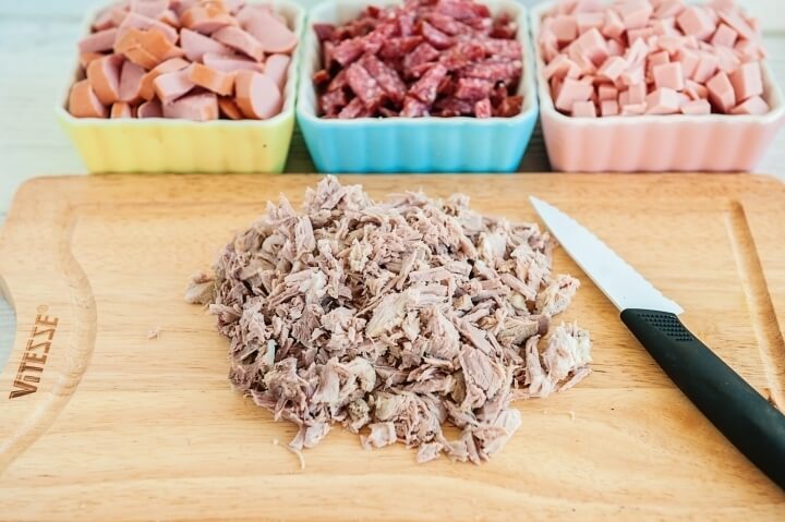 Мясо из бульона нарежем небольшими кусочками, а сосиски колечками. Колбасу и ветчины нарежем брусочками.