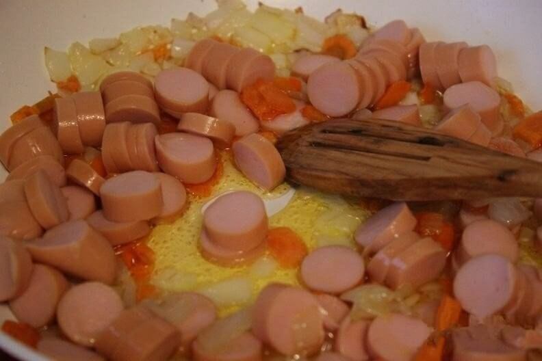 Сосиски нарезаем колечками, а затем отправляем обжариваться вместе с луком и морковью.
