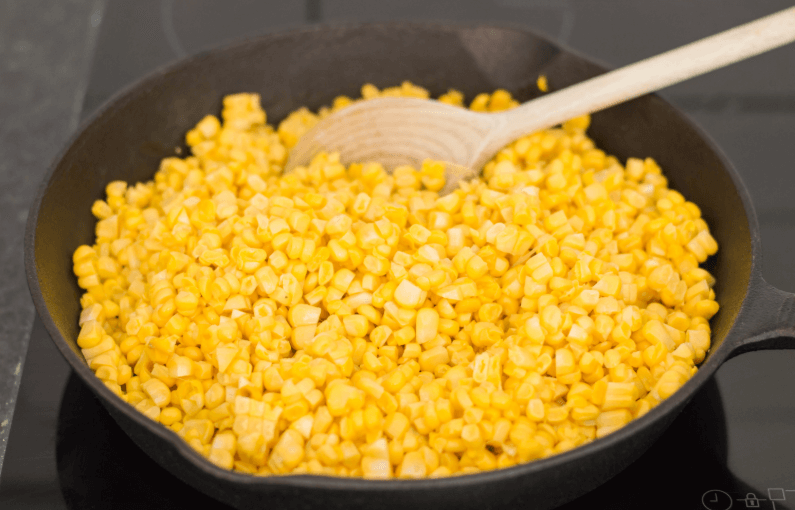 На сковороду отправляйте кукурузу, периодически перемешивая в течение 15-20 минут.