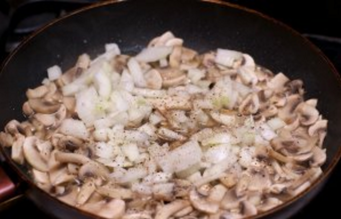 Теперь к грибочкам мы добавляем измельчённый репчатый лук и добавим соль, чёрный молотый перец. Хорошенько смешав жарим, пока лук не станет прозрачным.